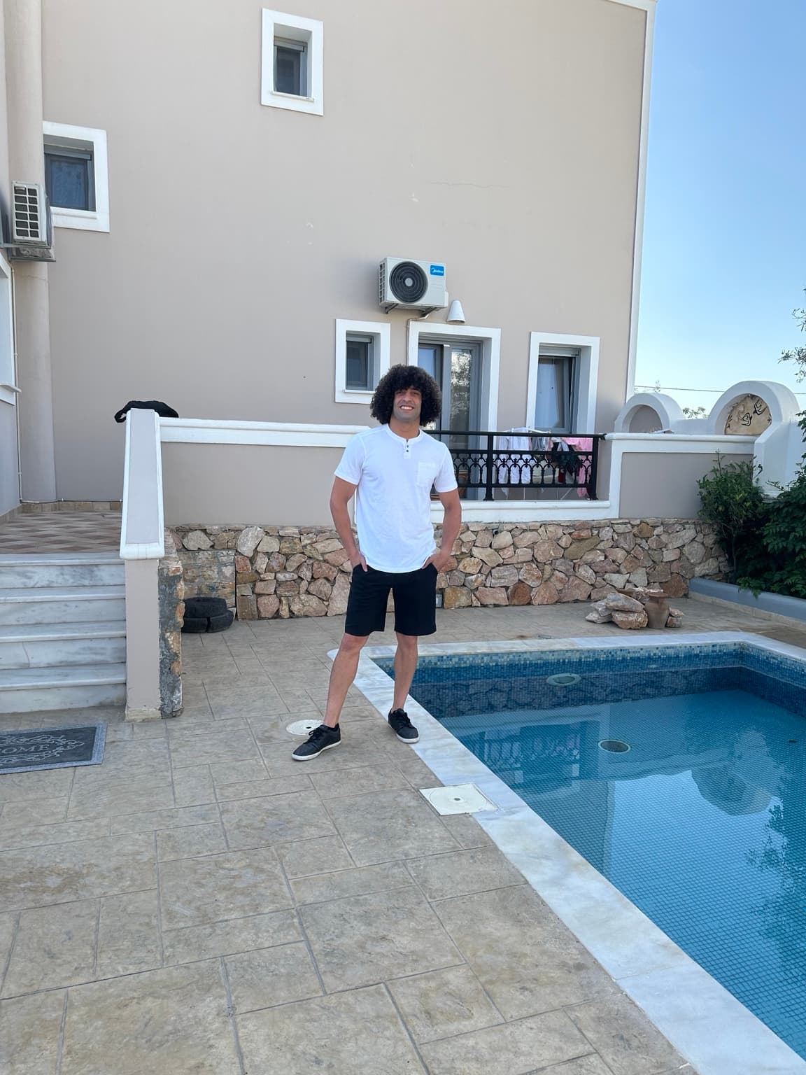 Ozzy wearing a white shirt by a pool